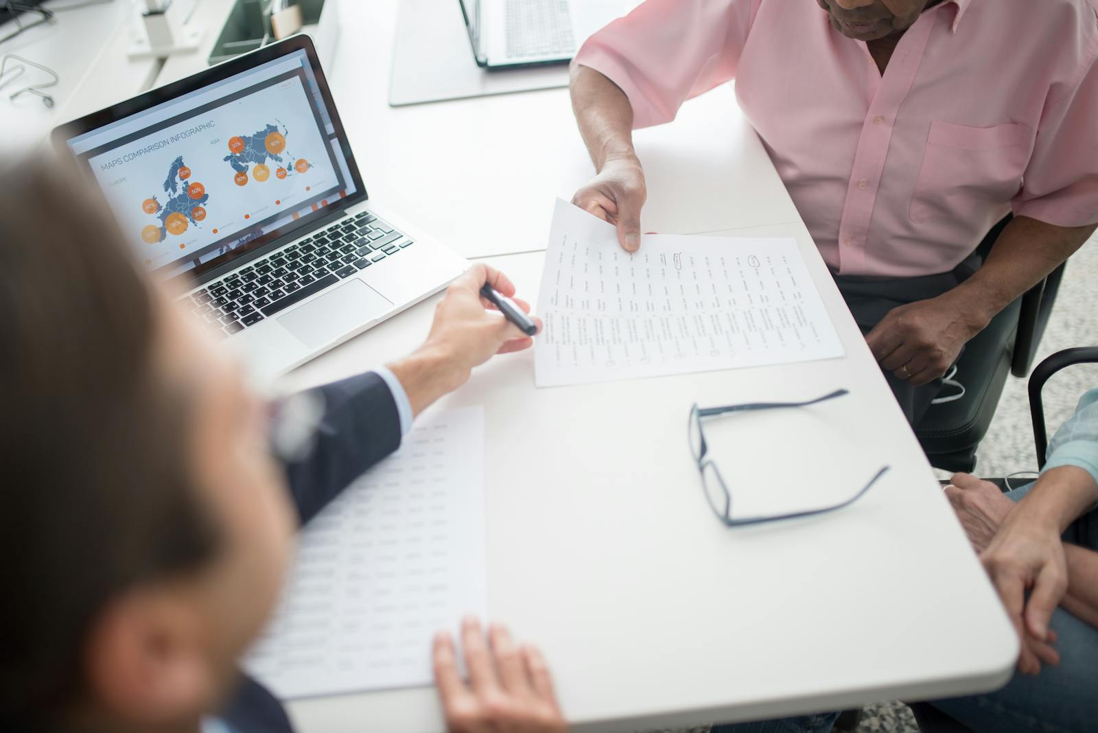 Senior couple reviewing documents with consultant at office desk with laptop.