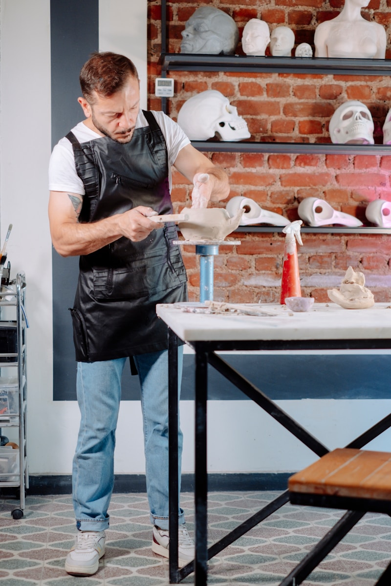 A man in an apron is making clay sculptures